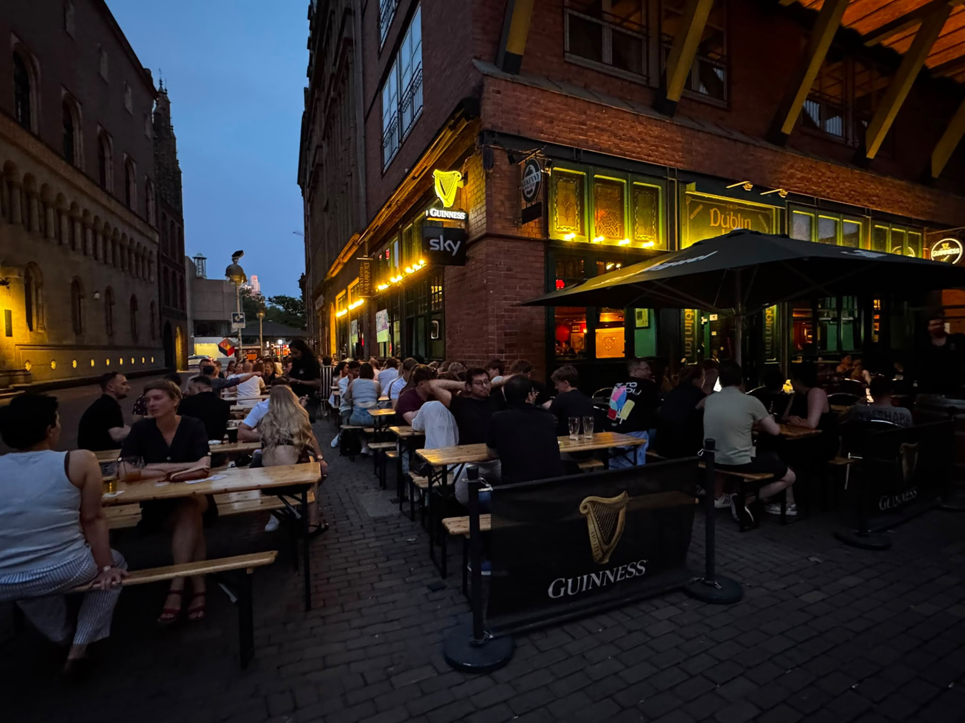 Guests enjoying the terrace beside Dublin Inn Hannover at dusk