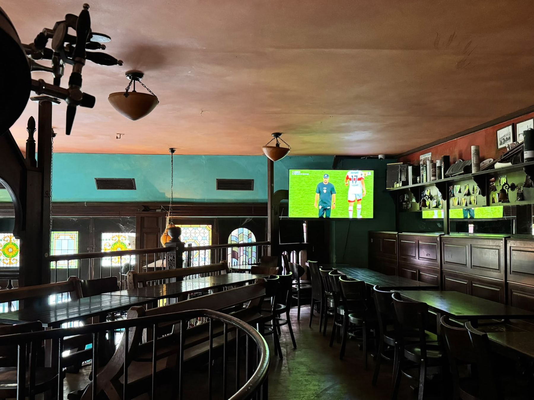 Upper gallery with tables and screens inside Dublin Inn Hannover